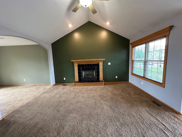 322 N 15th Ave, Winterset, IA 50273 - unfurnished living room featuring a ceiling fan, carpet, lofted ceiling, a tile fireplace, and arched walkways