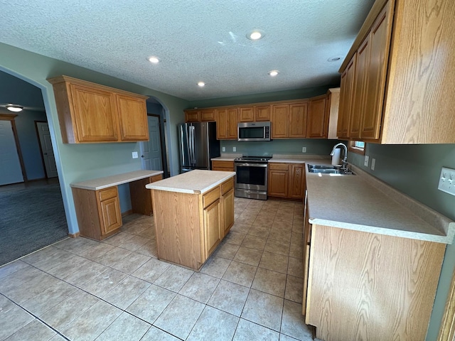 322 N 15th Ave, Winterset, IA 50273 - kitchen with stainless steel appliances, a sink, arched walkways, a center island, and a textured ceiling