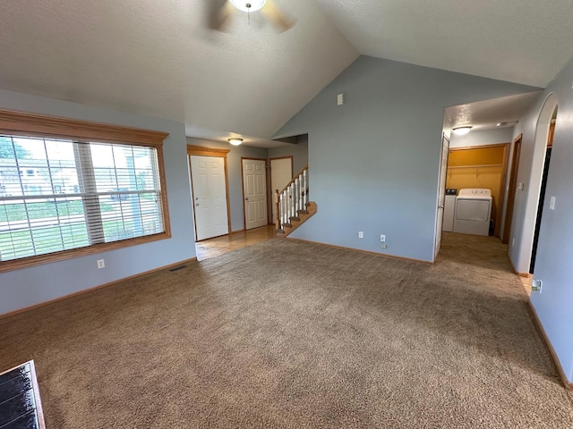 322 N 15th Ave, Winterset, IA 50273 - unfurnished living room featuring washing machine and dryer, vaulted ceiling, carpet flooring, ceiling fan, and baseboards