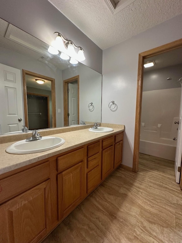 322 N 15th Ave, Winterset, IA 50273 - full bathroom with double vanity, a tub, and a textured ceiling