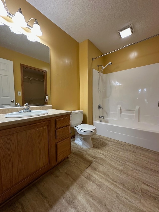 322 N 15th Ave, Winterset, IA 50273 - full bathroom with toilet, a chandelier, a textured ceiling, washtub / shower combination, and vanity