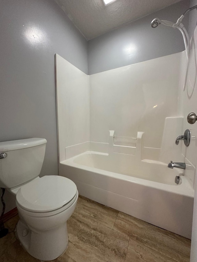 322 N 15th Ave, Winterset, IA 50273 - bathroom featuring a textured ceiling, toilet, and tub / shower combination