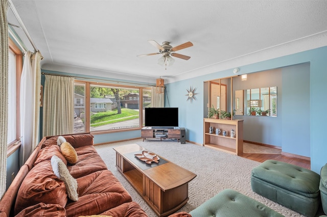 living area with a ceiling fan and baseboards