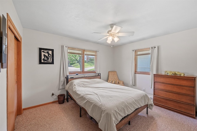 bedroom with light colored carpet, baseboards, a closet, and ceiling fan