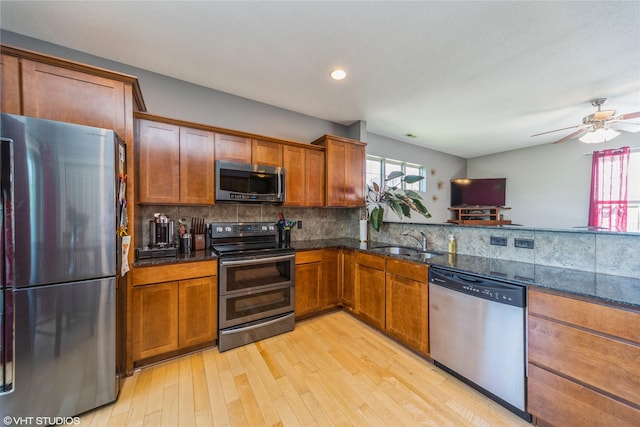 kitchen featuring stainless steel appliances, a sink, plenty of natural light, light wood finished floors, and recessed lighting