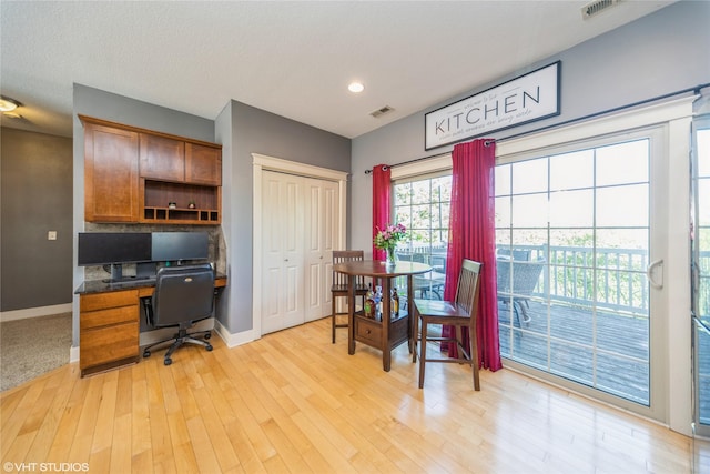 home office featuring baseboards, light wood finished floors, recessed lighting, and built in study area