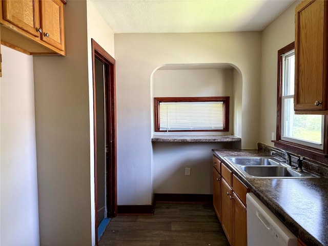 2036 Capitol Ave, Des Moines, IA 50317 - kitchen with white dishwasher, a sink, dark countertops, dark wood-style floors, and brown cabinets