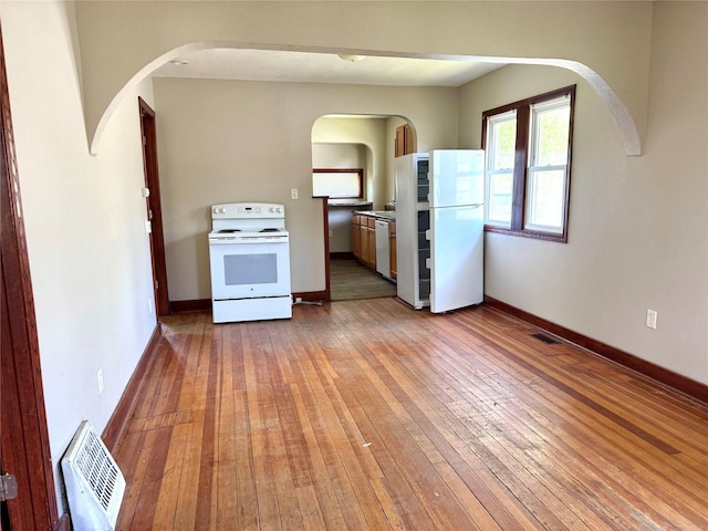 2036 Capitol Ave, Des Moines, IA 50317 - kitchen featuring white appliances, arched walkways, wood-type flooring, and baseboards