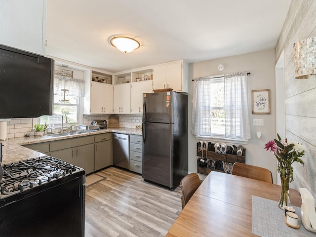 kitchen featuring black appliances, healthy amount of natural light, a sink, and decorative backsplash