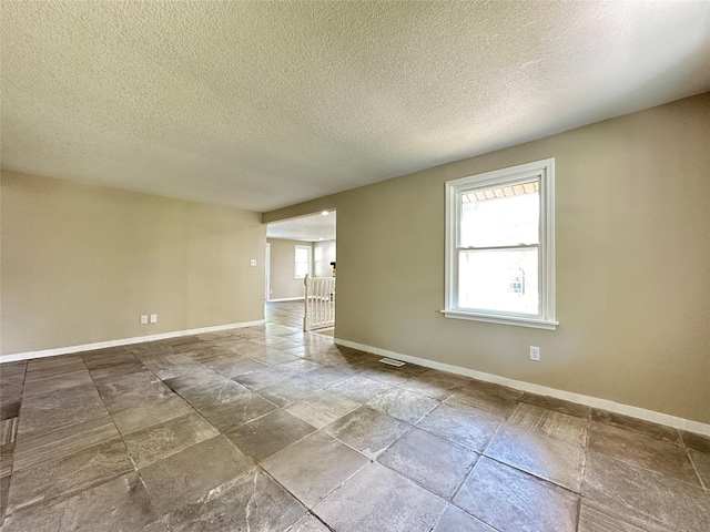 3429 54th St, Des Moines, IA 50310 - empty room with baseboards, a textured ceiling, and stone finish floors