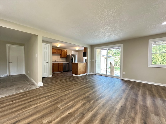 3429 54th St, Des Moines, IA 50310 - unfurnished living room featuring a textured ceiling, dark wood-type flooring, baseboards, and a sink