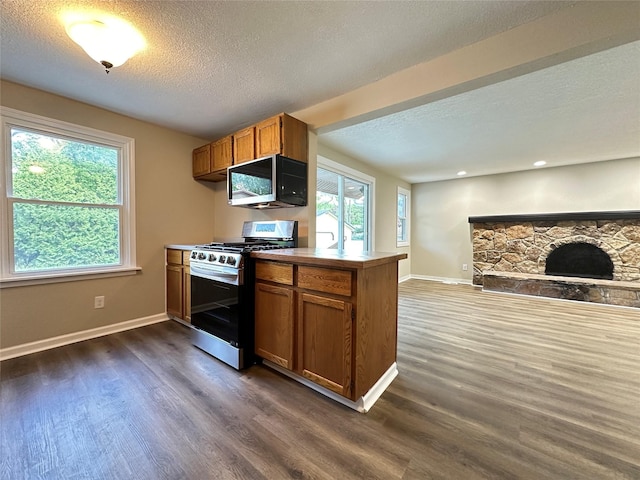 3429 54th St, Des Moines, IA 50310 - kitchen with stainless steel appliances, dark wood-style flooring, brown cabinets, baseboards, and a textured ceiling