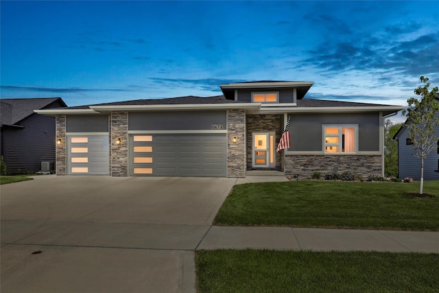 prairie-style house featuring stone siding, an attached garage, a front yard, driveway, and stucco siding