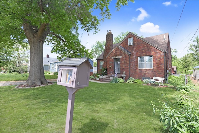 view of front of house with a chimney, brick siding, an outdoor structure, and a storage unit