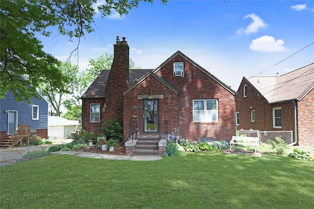 view of front of property featuring a chimney, a front yard, and brick siding