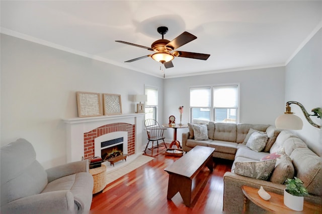living room with wood finished floors, ornamental molding, a fireplace, and a ceiling fan