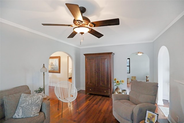 sitting room featuring arched walkways, dark wood-type flooring, a ceiling fan, ornamental molding, and baseboards