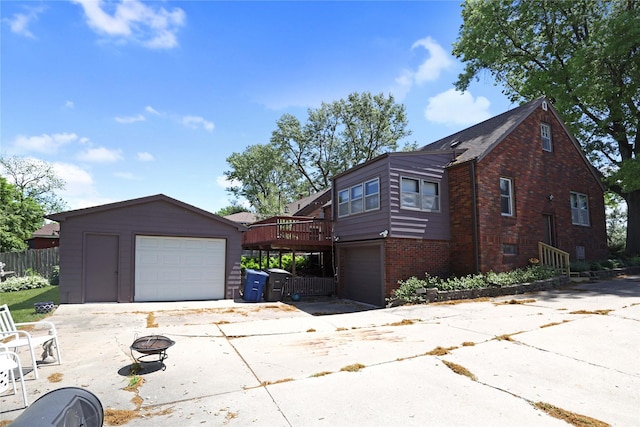 view of side of property with brick siding, concrete driveway, a detached garage, and an outdoor structure