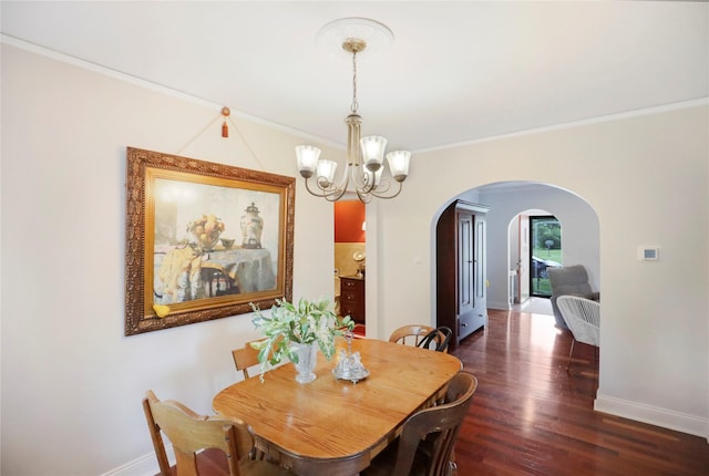 dining room featuring arched walkways, a chandelier, baseboards, crown molding, and wood finished floors
