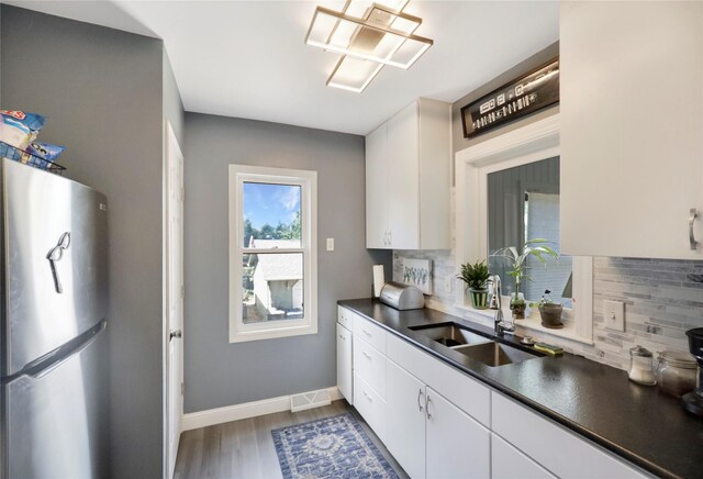 4027 Fagen Dr, Des Moines, IA 50310 - kitchen with freestanding refrigerator, dark countertops, backsplash, a sink, and white cabinets