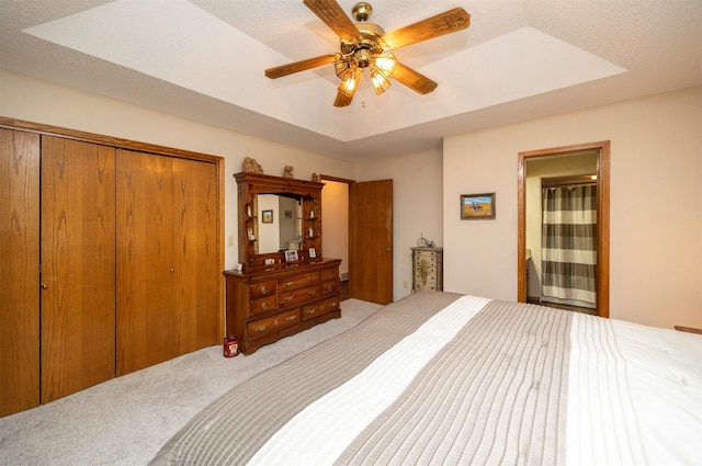 10760 Elmcrest Dr, Clive, IA 50325 - carpeted bedroom featuring a closet, a tray ceiling, ceiling fan, and connected bathroom