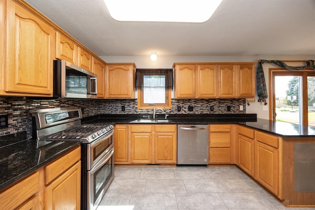 5433 NW 89th St, Johnston, IA 50131 - kitchen with stainless steel appliances, a sink, a peninsula, backsplash, and dark stone countertops