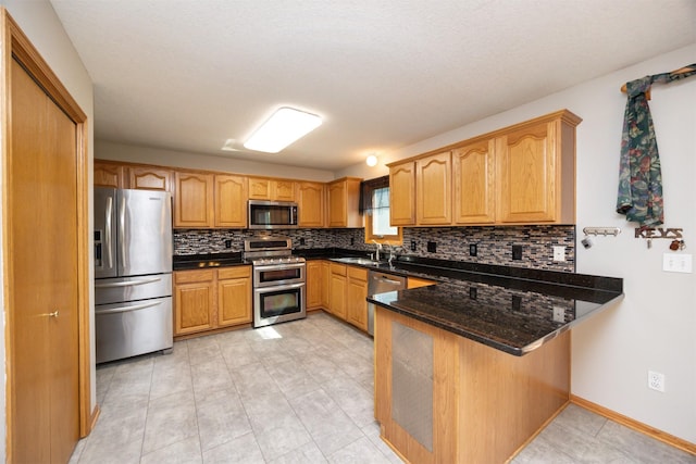 5433 NW 89th St, Johnston, IA 50131 - kitchen featuring stainless steel appliances, a peninsula, tasteful backsplash, dark stone counters, and a sink