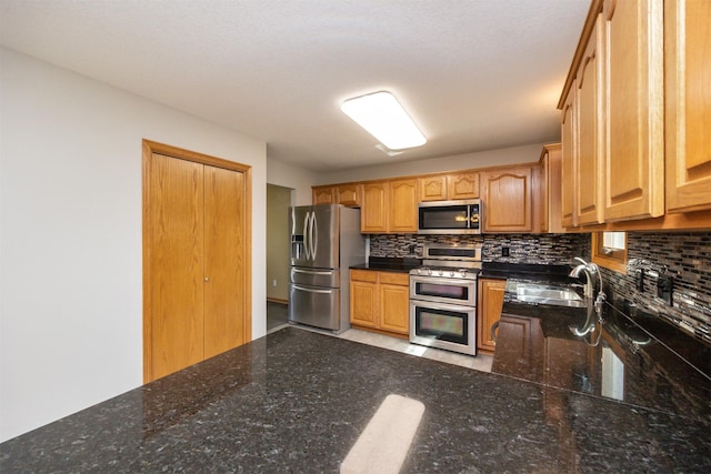 5433 NW 89th St, Johnston, IA 50131 - kitchen featuring stainless steel appliances, a sink, decorative backsplash, and dark stone countertops