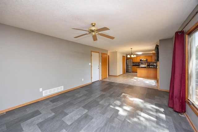 5433 NW 89th St, Johnston, IA 50131 - unfurnished living room featuring a chandelier, a ceiling fan, baseboards, and a textured ceiling