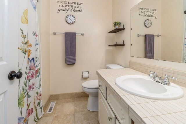 604 NE 8th St, Grimes, IA 50111 - full bathroom featuring baseboards, toilet, vanity, backsplash, and tile patterned floors