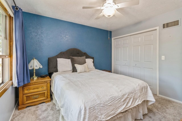 604 NE 8th St, Grimes, IA 50111 - carpeted bedroom featuring multiple windows, a closet, a textured ceiling, baseboards, and a ceiling fan