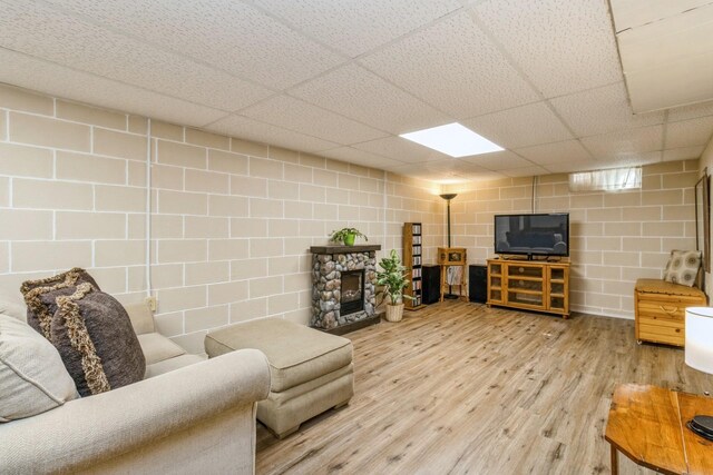 604 NE 8th St, Grimes, IA 50111 - living area featuring wood finished floors, concrete block wall, a drop ceiling, and a stone fireplace