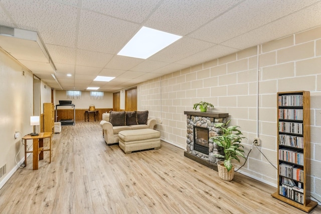 604 NE 8th St, Grimes, IA 50111 - living area featuring wood finished floors, a stone fireplace, baseboards, and a drop ceiling