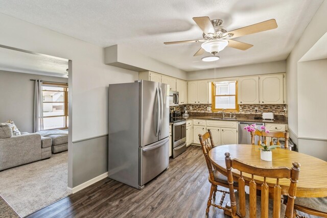 604 NE 8th St, Grimes, IA 50111 - kitchen with stainless steel appliances, ceiling fan, dark countertops, backsplash, and dark wood-style flooring