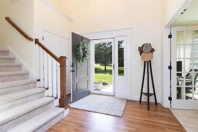 entrance foyer with stairway, wood finished floors, a towering ceiling, and baseboards