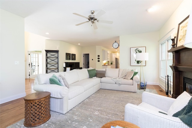 living room featuring a ceiling fan, wood finished floors, baseboards, a glass covered fireplace, and recessed lighting