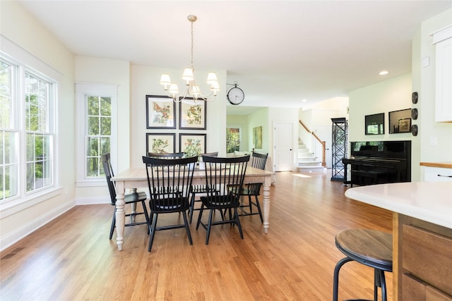 dining room with light wood finished floors, plenty of natural light, stairs, a chandelier, and recessed lighting
