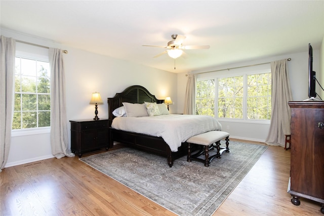 bedroom with light wood finished floors, baseboards, and ceiling fan