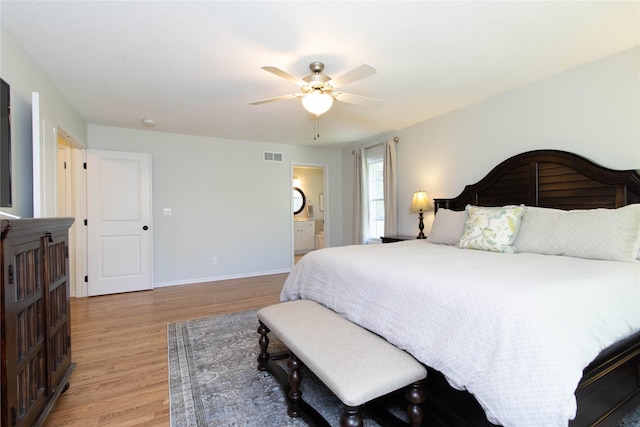 bedroom with light wood finished floors, baseboards, ceiling fan, and connected bathroom
