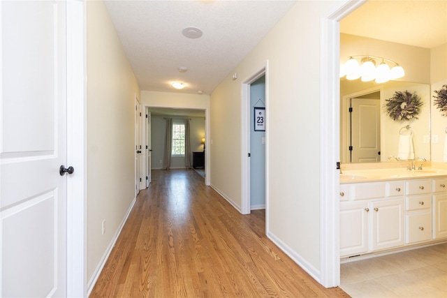 hallway with light wood-type flooring and baseboards