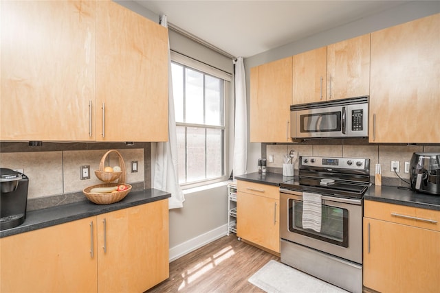 400 Walnut St Unit 201, Des Moines, IA 50309 - kitchen featuring stainless steel appliances, tasteful backsplash, baseboards, light wood finished floors, and dark countertops