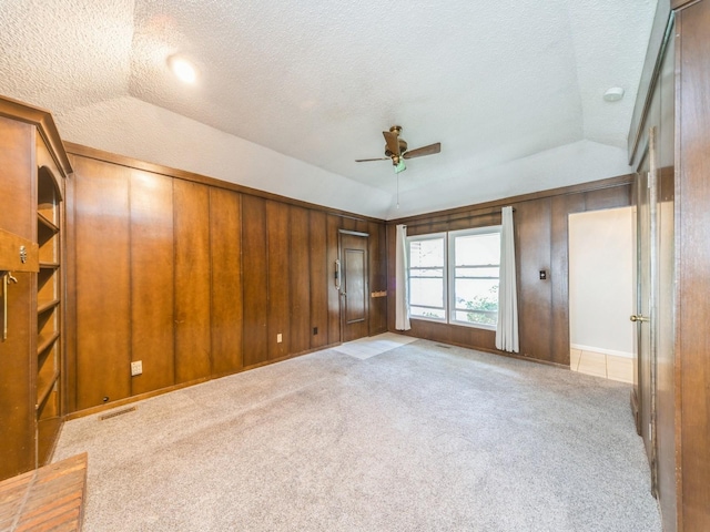 3800 Western Hills Dr, West Des Moines, IA 50265 - unfurnished bedroom with vaulted ceiling, a textured ceiling, carpet floors, and wood walls