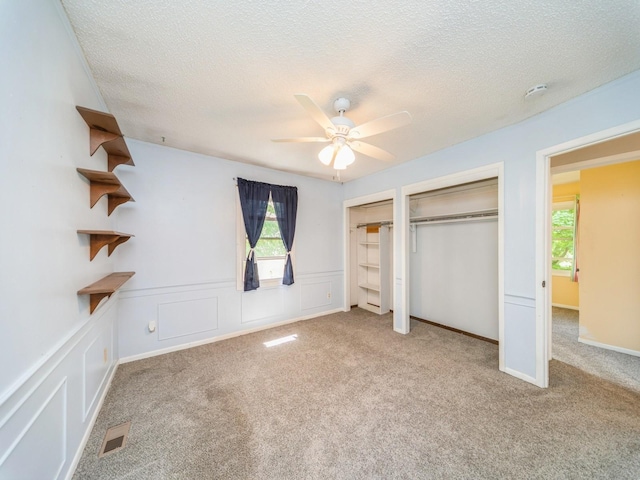 3800 Western Hills Dr, West Des Moines, IA 50265 - unfurnished bedroom featuring multiple closets, a textured ceiling, carpet, ceiling fan, and wainscoting