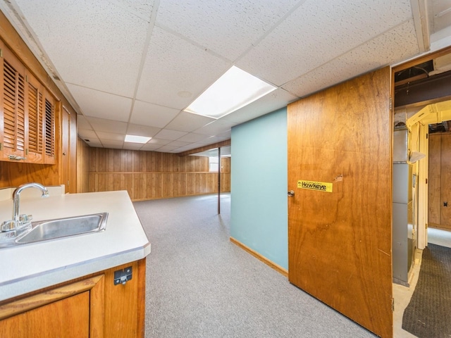 3800 Western Hills Dr, West Des Moines, IA 50265 - kitchen with a sink, wooden walls, carpet floors, a drop ceiling, and brown cabinetry