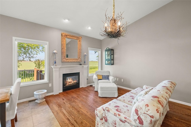 4400 132nd St, Urbandale, IA 50323 - living room featuring a chandelier, a glass covered fireplace, vaulted ceiling, baseboards, and wood finished floors