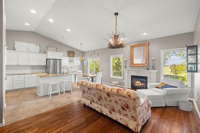 4400 132nd St, Urbandale, IA 50323 - living area featuring a chandelier, vaulted ceiling, recessed lighting, a glass covered fireplace, and light wood finished floors