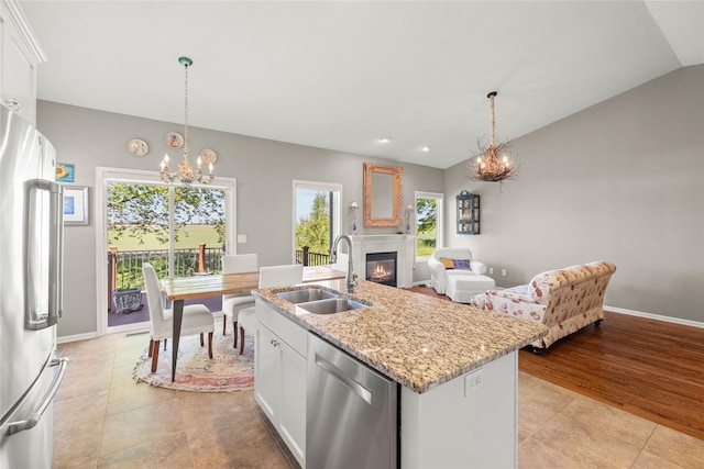 4400 132nd St, Urbandale, IA 50323 - kitchen with stainless steel appliances, a sink, a chandelier, a glass covered fireplace, and white cabinets