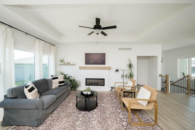 16427 N Valley Dr, Urbandale, IA 50323 - living area featuring a raised ceiling, wood finished floors, ceiling fan, and a glass covered fireplace