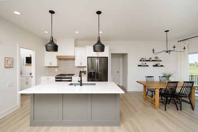 16427 N Valley Dr, Urbandale, IA 50323 - kitchen featuring stainless steel appliances, light wood finished floors, tasteful backsplash, white cabinets, and an island with sink