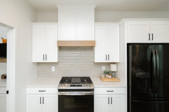 16427 N Valley Dr, Urbandale, IA 50323 - kitchen featuring black fridge with ice dispenser, stainless steel range with gas stovetop, decorative backsplash, white cabinetry, and light stone countertops